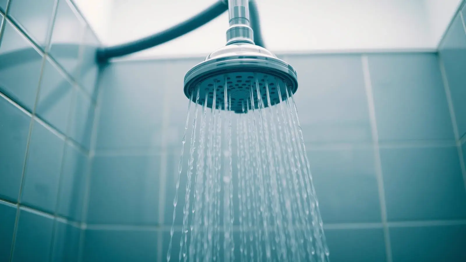 Hand testing the temperature of water running from a residential shower head